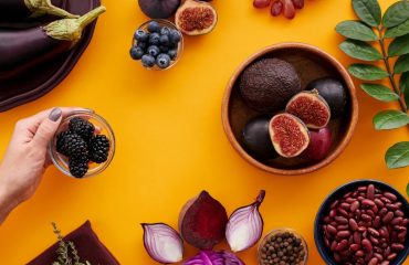 Colorful assortment of fruits and vegetables on a yellow backdrop, highlighting healthy eating.